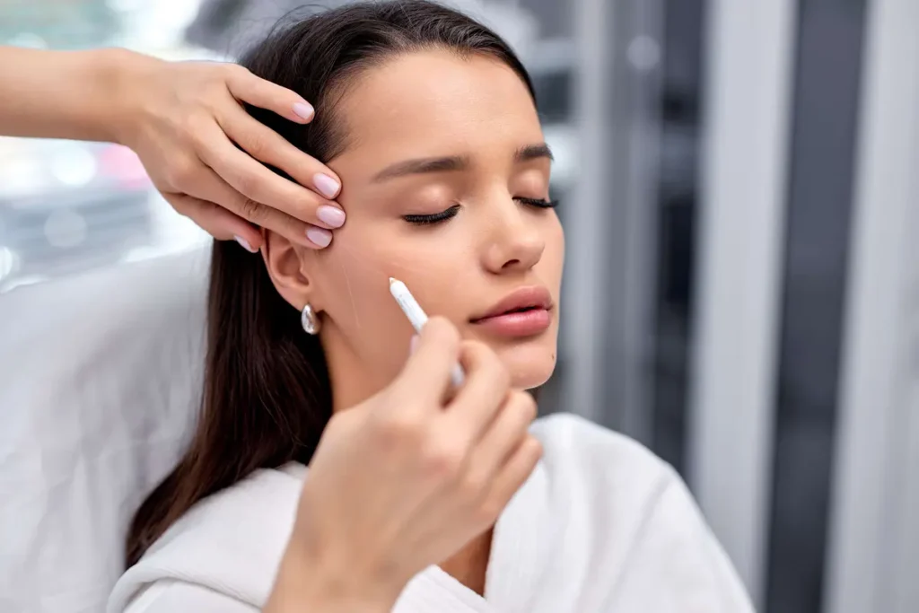 Woman receiving facial contouring treatment along the jawline with a beauty product applicator